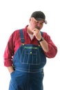 Big man in overalls and cap standing thinking Royalty Free Stock Photo