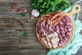 Big meat set. Homemade smoked pork-beef sausage, salted bacon, basturma chopped slices on a wooden board with spices and herbs. Royalty Free Stock Photo