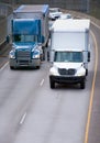 Big and middle rigs semi trucks driving on turning overpass road Royalty Free Stock Photo