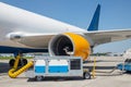 Big modern commercial cargo freight plane parked on airport runway and connected to ground supply power unit. Aircraft