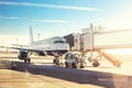 Big modern commercial plane on airfield docked with boarding bridge at sunrise or sunset. Blue clear sky on background. Travel and Royalty Free Stock Photo