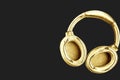 Big modern golden headphones isolated on black background.