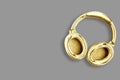 Big modern golden headphones isolated on grey background.