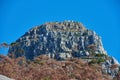 A big mountain with brown and green trees against a background of clear blue sky and copyspace. Huge rocky terrain