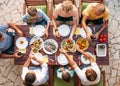 Big multigenerational family dinner in process. Top view image on table with food and hands. Food consumption and