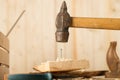 Big nail. A man in white gloves is hammering a big nail on the desk with black background. Shiny scrached hammer