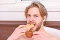 Big naked muscular man having fun in bedroom. Pleasant beginning of day. Handsome young man drink coffee and eating