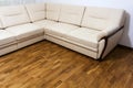 Big new beige sofa on wooden parquet floor Royalty Free Stock Photo