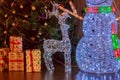 Big New Year`s Figures of a snowman, a deer and gifts from glowing multicolored garlands on the background of a decorated artific Royalty Free Stock Photo