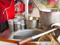 Big noodle broth pot, buckets, ladle, ingredient containers, and stanless cooking counter at a busy small noodles restaurant in