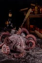 Big octopus against of on dark background with old vintage dishes and bottle of rum. Preparation delicious dinner