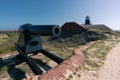 Big old black cannon on a steel carriage with wheels and a lighthouse on a rooftop of old military fort in Florida. Royalty Free Stock Photo