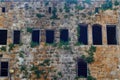 Big old brown bricks wall with plants growing on it in an old city in middle east Royalty Free Stock Photo