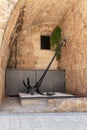 Big old iron anchor, rusty and black in the courtyard of the Crusader fortress of the old city of Acre in northern Israel
