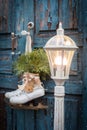 Big old lantern and a pair of vintage white ice skates with Christmas decoration hanging on the blue rustic door Royalty Free Stock Photo