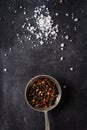 Big old spoon with peppercorn and salt pile on black background Royalty Free Stock Photo