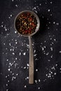 Big old spoon with peppercorn and salt pile on black background Royalty Free Stock Photo