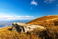 Big old stone lies on grassy hill in highland under blue sky