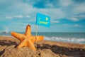 Big orange starfish with flag at the seashore