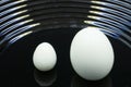 Big ostrich egg and chicken egg in glasses on table . Royalty Free Stock Photo