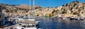 Big panorama view on Greek sea Symi island harbor port, houses on island hills.