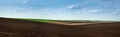 panoramic view of colorful hills of plowed dark land and green fields