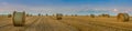 big panoram of harvested wheat field, bales of straw in rolls, against the background of a beautiful sky Royalty Free Stock Photo