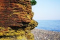 A big part of the red-brown rock closeup against the blue sea Royalty Free Stock Photo