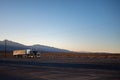 Big Peterbilt long nose truck with a large trailer driving on the deserted roads at sunset