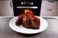 Big piece of meat on plate. Roast beef close-up. Barbecue meat in modern kitchen. Blurred background oven. Hot cooked dinner. Big Royalty Free Stock Photo