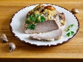 Big Piece and slice of Slow Cooked Oven-Barbecued Pulled Pork shoulder on chopping board with garlic on plate, view from