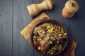 Big pieces of pork in a pan with vegetables and corn in a cast iron pan