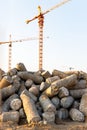 Big pile of cut concrete piles at construction site, tower cranes on background Royalty Free Stock Photo