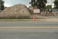 big pile of dirt behind silver fence with building permits on bulletin board. p Royalty Free Stock Photo