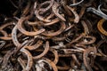 Big pile of large rusty old worn stainless steel iron metal lucky horse shoes and tacks nails removed by farrier Royalty Free Stock Photo