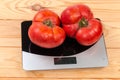 Big pink tomatoes on digital kitchen scale on rustic table Royalty Free Stock Photo