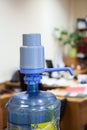 Big plastic bottle with blue pump dispenser in an office