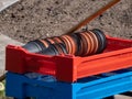 Big plastic box full with empty brown and black plastic pots stacked together for plants with flower bed in the background in Royalty Free Stock Photo