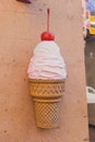 Big plastic ice cream cone sign of cafe or candy shop on city urban street - dessert and summer sweets concept Royalty Free Stock Photo