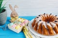 Big plate with cake and hand painted colorful eggs, on towel on blue background. Close up. Decoration for Easter, Royalty Free Stock Photo