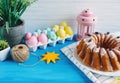 Big plate with cake and hand painted colorful eggs, on towel on blue background. Close up. Decoration for Easter, Royalty Free Stock Photo