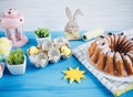 Big plate with cake and hand painted colorful eggs, on towel on blue background. Close up. Decoration for Easter, Royalty Free Stock Photo
