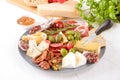 Big plate with variety of cheeses, sausages served with sun dried tomatoes, olives and seasoning on white table Royalty Free Stock Photo