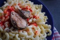 Big portion of pasta with fish on blue plate, close up shot. Macaroni with pilchard or sardine with hot tomato sauce. Overeating Royalty Free Stock Photo