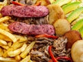 Big portion of pork meat, grilled sausages, potatoes and arepas with avocados Royalty Free Stock Photo