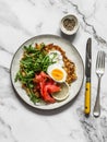 Big potato rosti with egg, arugula, salmon and Greek yogurt sauce on a light background, top view. Delicious food