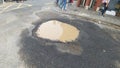 Big pothole filled with muddy water on the road at junction Royalty Free Stock Photo