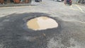 Big pothole filled with muddy water on the road at junction Royalty Free Stock Photo