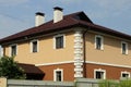 Big private house with windows under a brown tiled roof with a chimneys