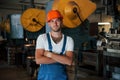 Big production machine behind. Portrait of engineer in metallurgical factory in protective helmet